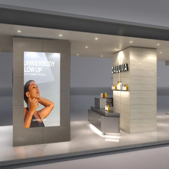 Ein modernes, minimalistisches Geschäft mit hellem Holz und grauen Akzenten zeigt Regale mit Flaschen. Ein großes Poster zeigt eine Frau, die sich im Sonnenlicht sonnt, mit dem Text "SUMMERBODY GLOW UP" und "DALUMA" über der Ladentheke.