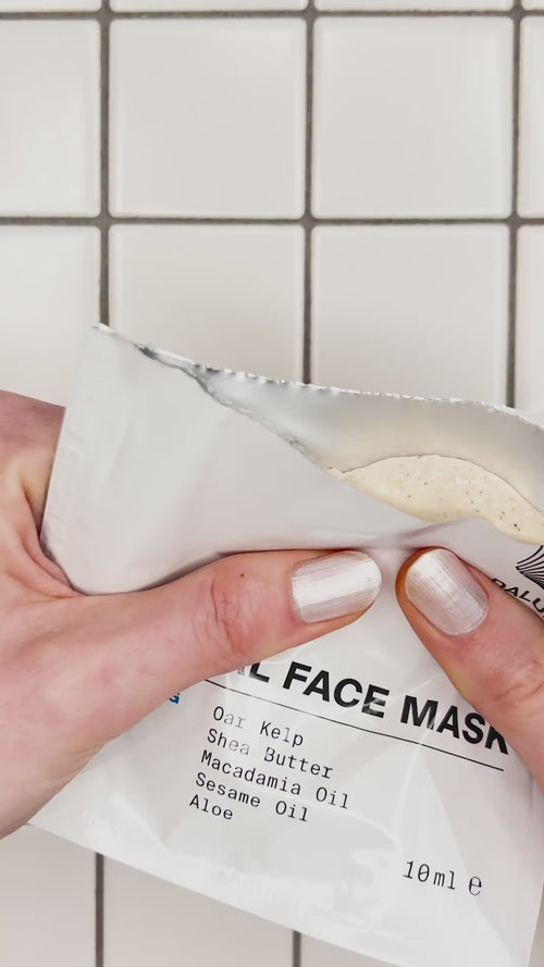 Eine Hand mit weiß lackierten Nägeln hält eine teilweise geöffnete weiße Packung Daluma DEEP HYDRATION FEUCHTIGKEITSMASKE, in der eine cremefarbene beigefarbene Maske zum Vorschein kommt.