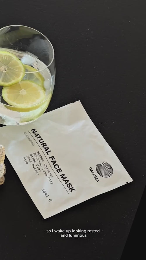 Ein Glas Wasser mit Zitronen- und Limettenscheiben steht neben einer ungeöffneten Packung DALUMA Natural Face Mask auf einer dunklen Fläche. Die Untertitel am unteren Rand lauten: Damit ich ausgeruht und strahlend aufwache.