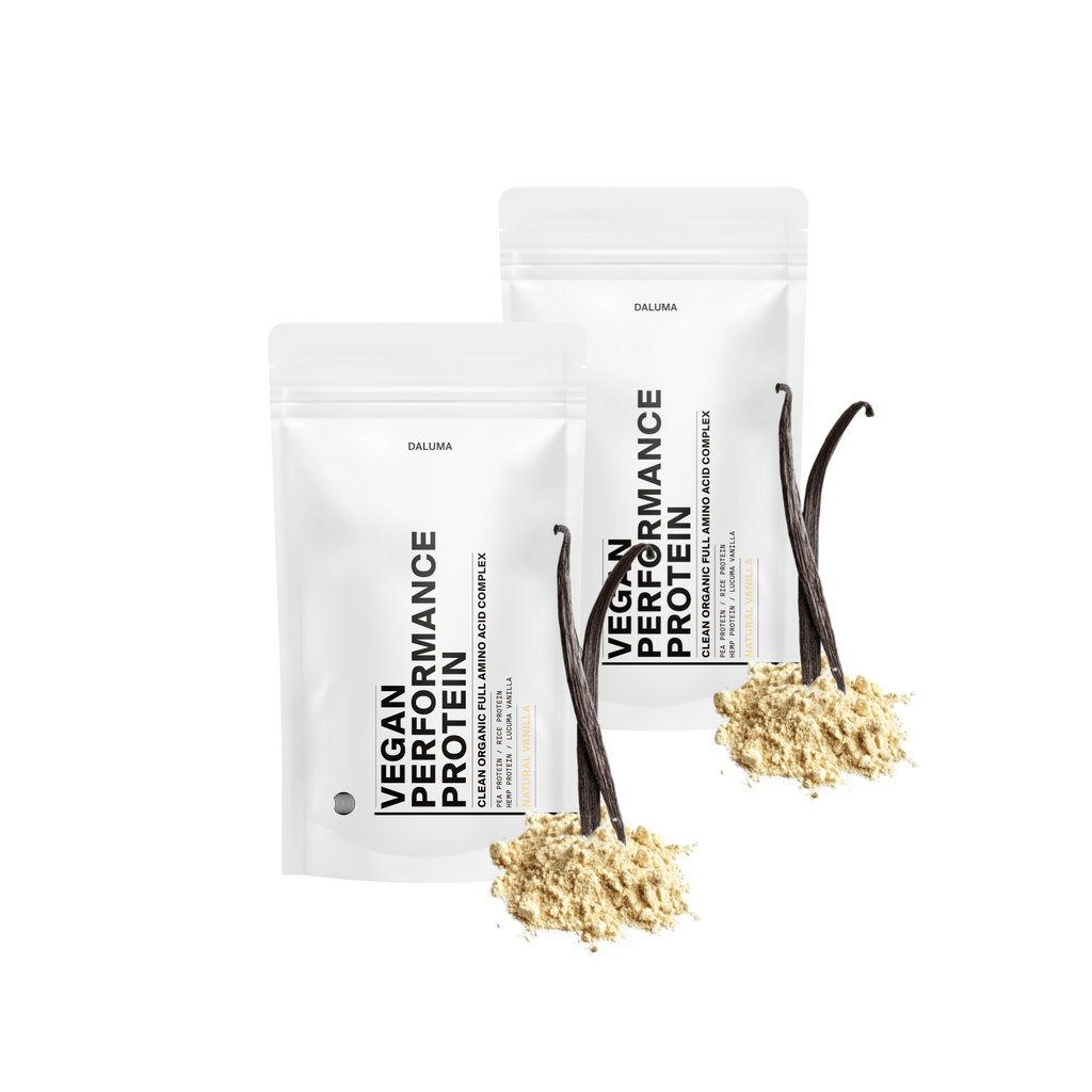 Zwei weiße DALUMA VEGANES PERFORMANCE PROTEIN VANILLE DOUBLE-Beutel (Vanille und Schokolade) liegen nebeneinander, beschriftet mit "pflanzliches Protein". Auf der Vorderseite befinden sich eine Vanilleschote und -pulver, die auf die Verwendung von natürlicher Vanille hinweisen.