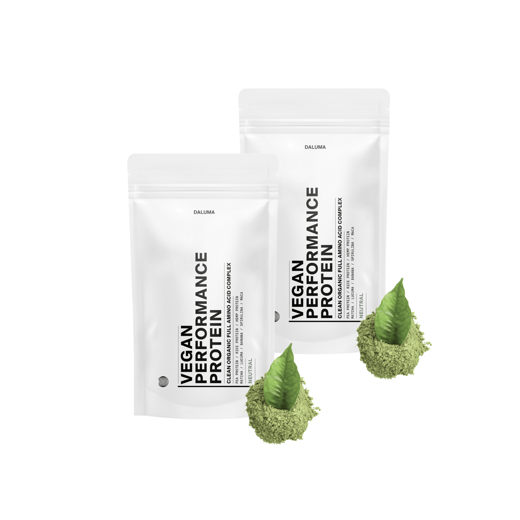 Zwei weiße DALUMA-Beutel mit der Aufschrift VEGANES PERFORMANCE PROTEIN NEUTRAL DOUBLE" stehen aufrecht neben grünen Pulverhaufen mit Blättern, die pflanzliches Protein für den Muskelaufbau präsentieren - alles vor einem sauberen weißen Hintergrund.